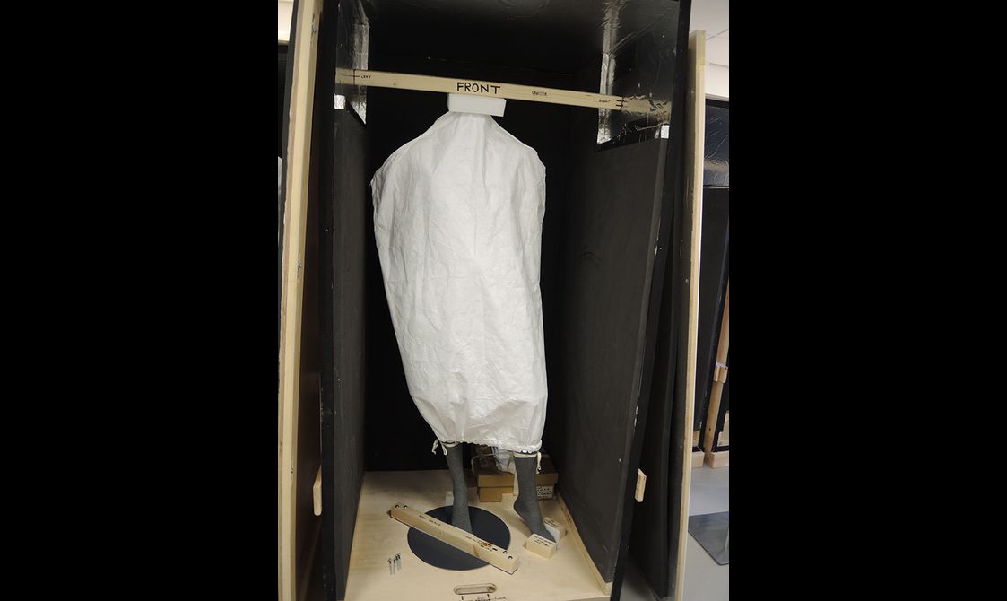 A mannequin packed into a crate. The mannequin is covered in white material.
